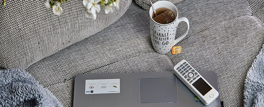 Eine Tasse Kaffe, ein Laptop und ein Telefon auf einem Sofa